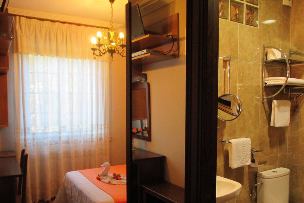 Ein Hotelzimmer mit Esstisch, einer Kristallleuchter, einem Spiegel, einem Waschbecken und einer Toilette.