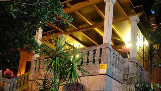 Un escalier en pierre menant à un bâtiment doté d’un toit en bois et de colonnes.