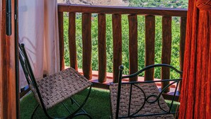 A balcony with a view of mountains, two chairs, and a wooden railing.