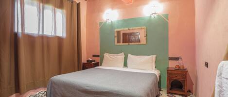 A bedroom with a bed, a nightstand, a wall-mounted light, and a patterned rug.