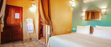 A room with a bed, a wooden wardrobe, a hanging light fixture, and a wall-mounted air conditioner.
