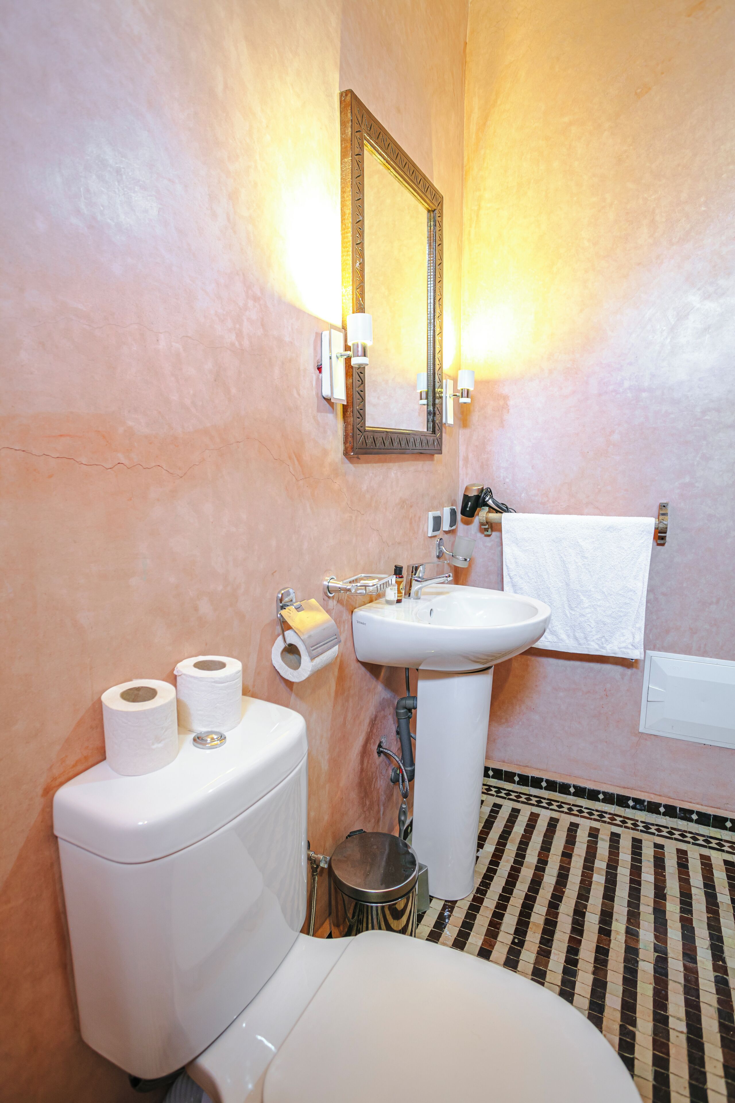 A bathroom with a toilet, sink, and mirror.