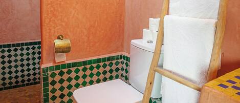 Un baño con inodoro, ducha, toallero y piso a cuadros.