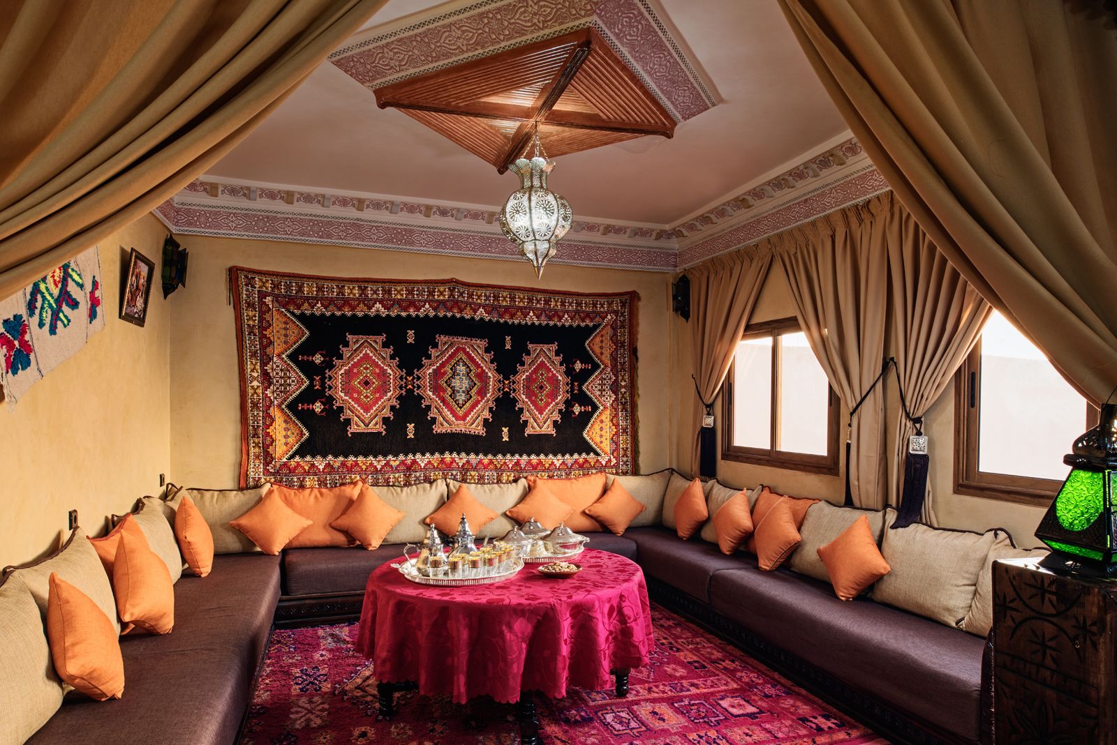 Une pièce au décor traditionnel, avec un ensemble de canapés, une tapisserie à motifs et un lustre.