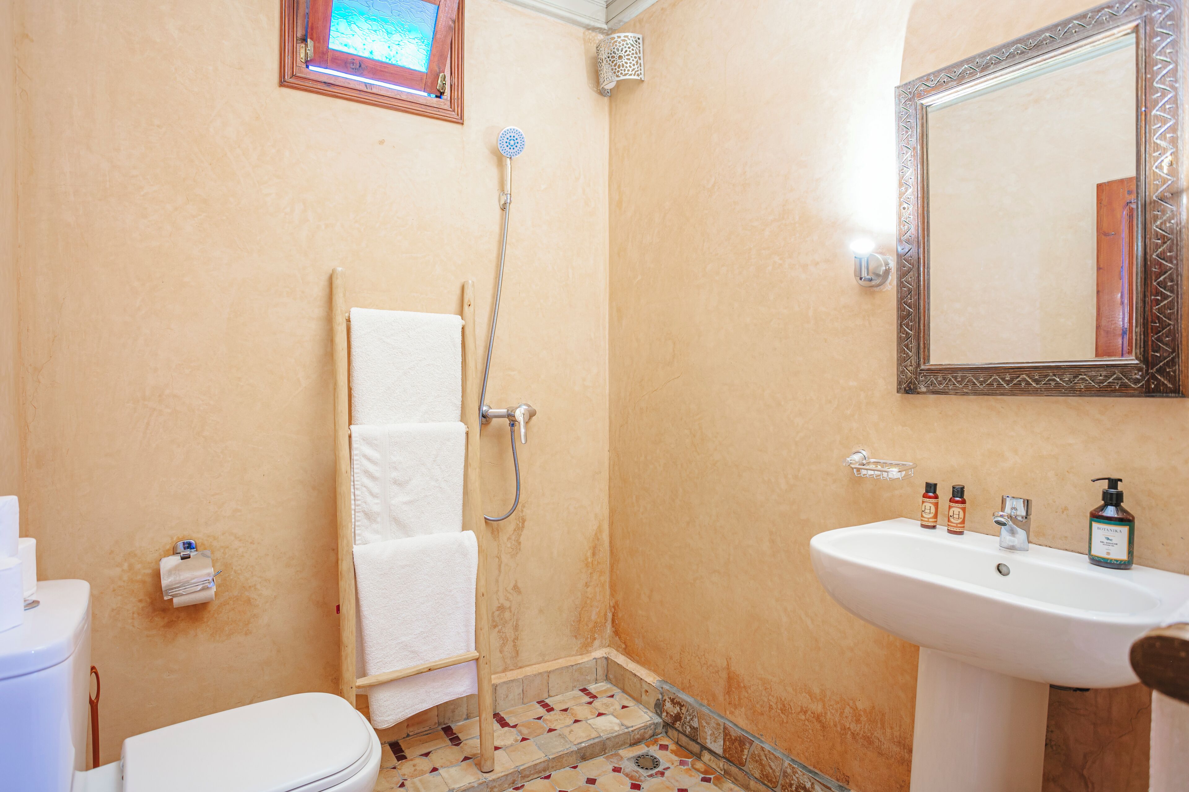 A bathroom with a toilet, a shower, a sink, and a mirror.
