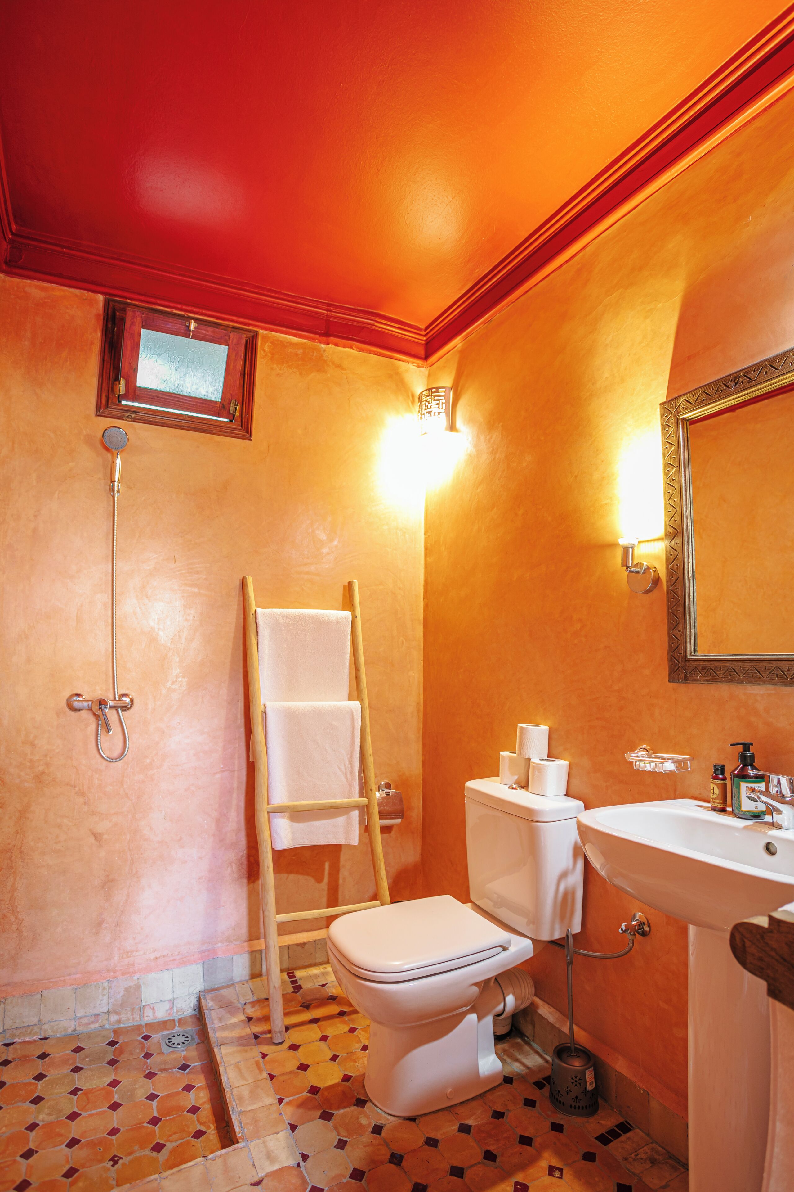 Un baño con inodoro, lavamanos, ducha y toallero.