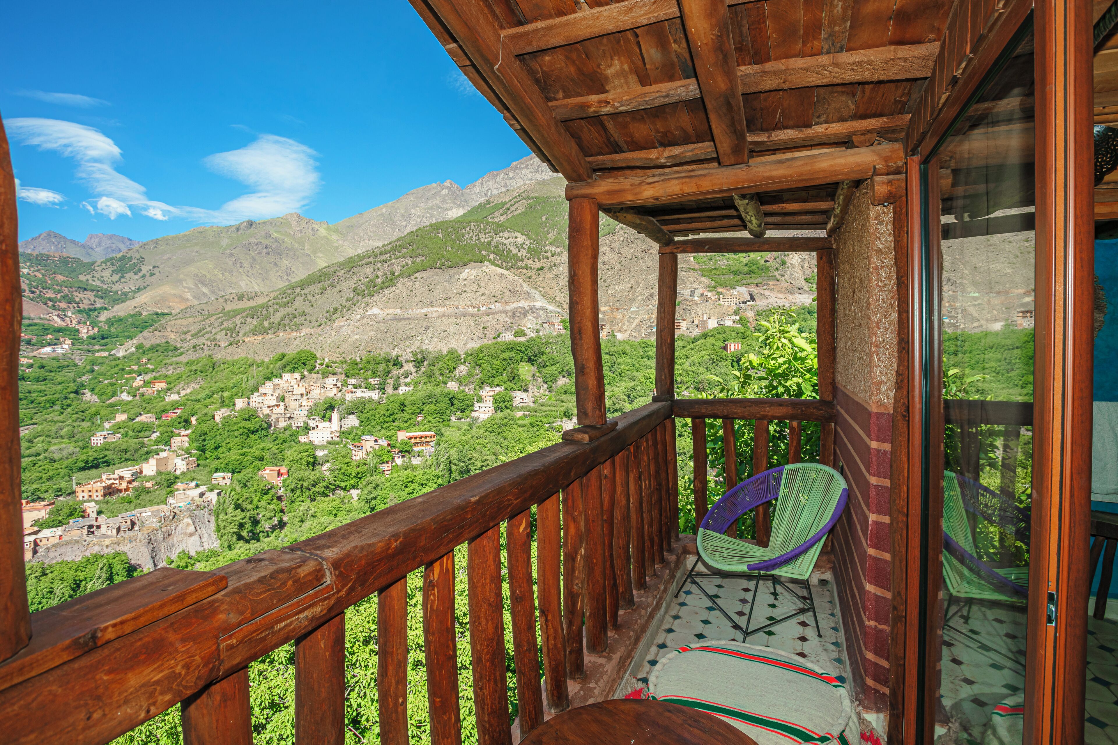 A wooden balcony with a view of a mountainous village.