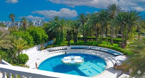 A circular pool with a central fountain, surrounded by lounge chairs and palm trees. - HAMILTON Agadir (Agadir)
