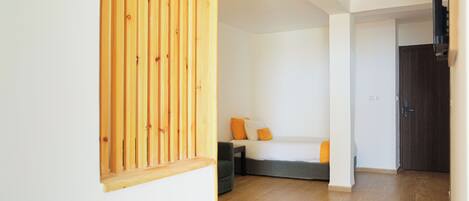 Una habitación con cama, escritorio, silla y un panel divisor de madera.