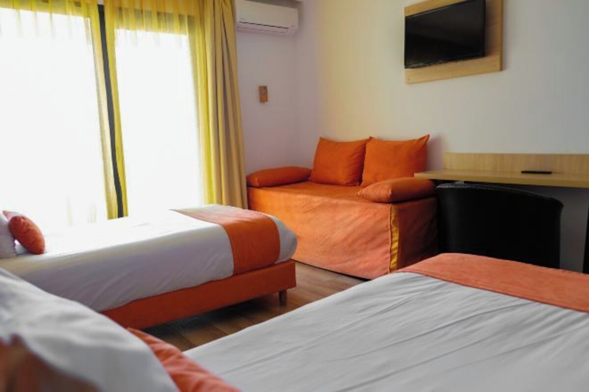 Habitación de hotel con dos camas, televisión y escritorio.