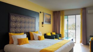 A hotel room with a large bed, a desk, a chair, and a view of the outdoors.