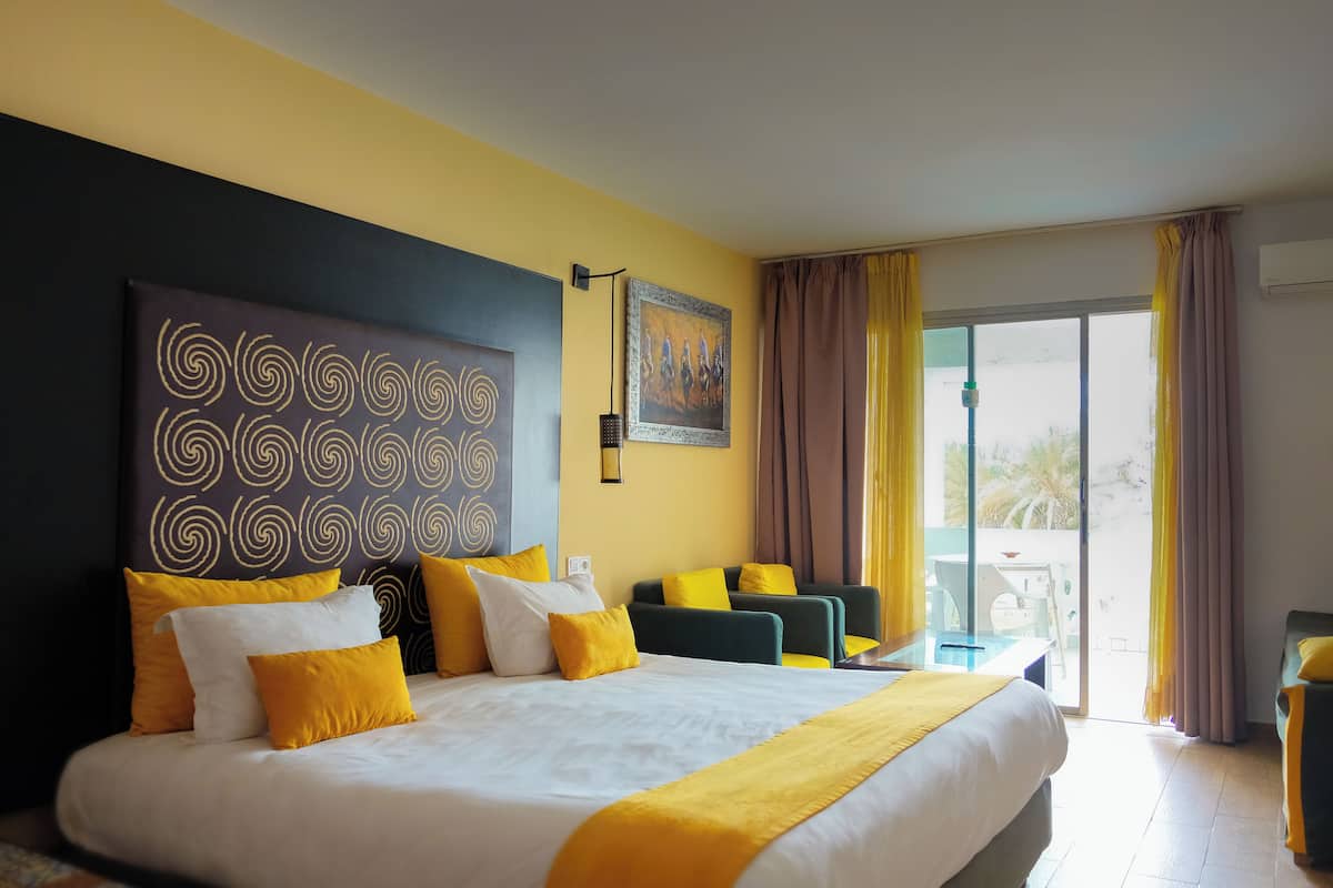 Quarto de hotel com uma cama grande, uma escrivaninha, uma cadeira e vista para o exterior.