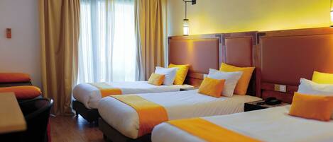 A hotel room with three beds, a desk, and a chair.