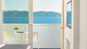 A hotel room with a bed, a round table with fruit and a drink, a chair, and a balcony with a view of the sea. - Sensimar Makarska (Podgora)