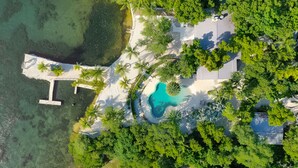 An aerial view of a resort with a swimming pool, palm trees, and a beach area. - Largo Resort (Key Largo)