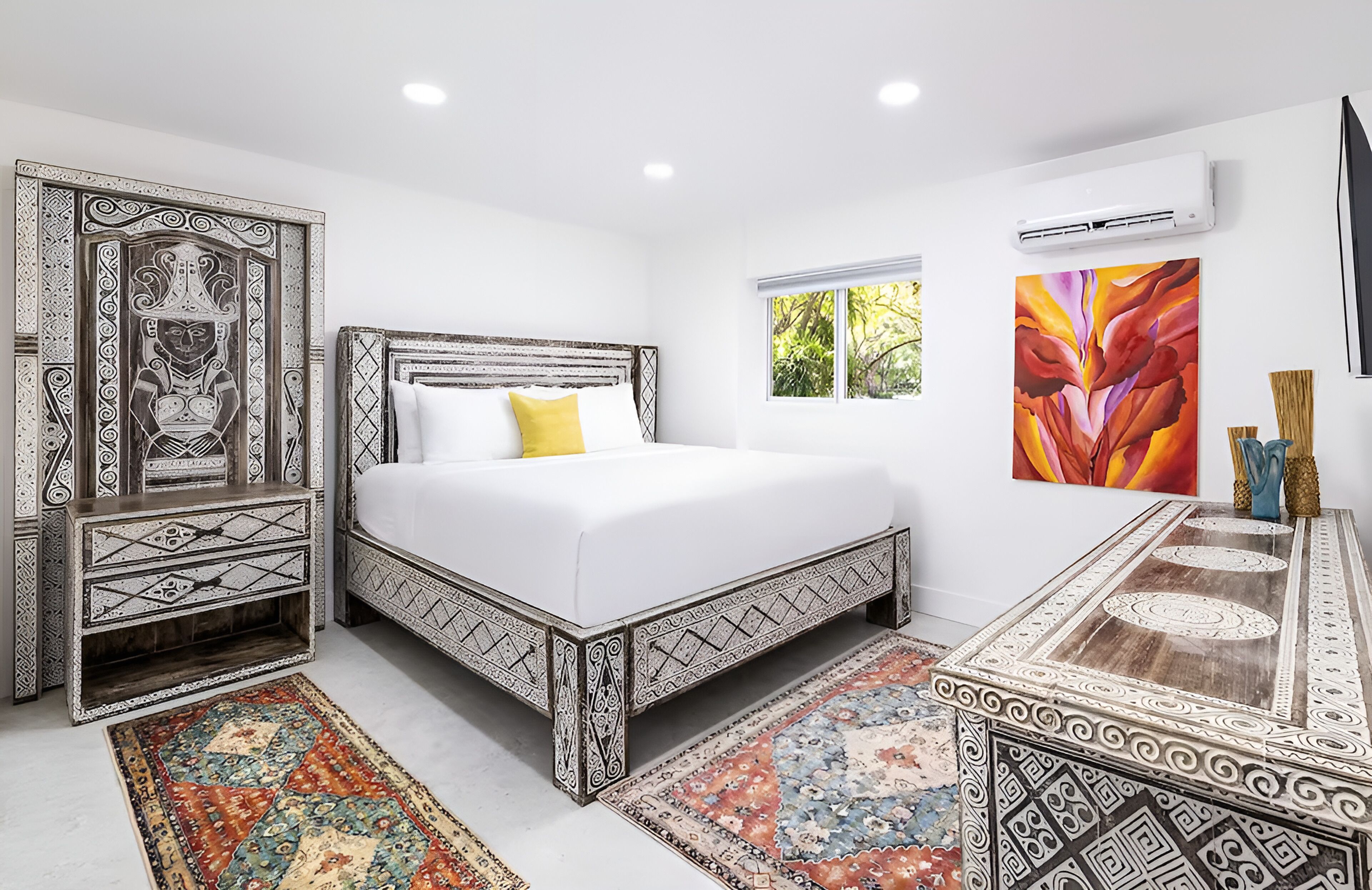 A bedroom with a bed, a nightstand, a decorative cabinet, a window, and a painting.