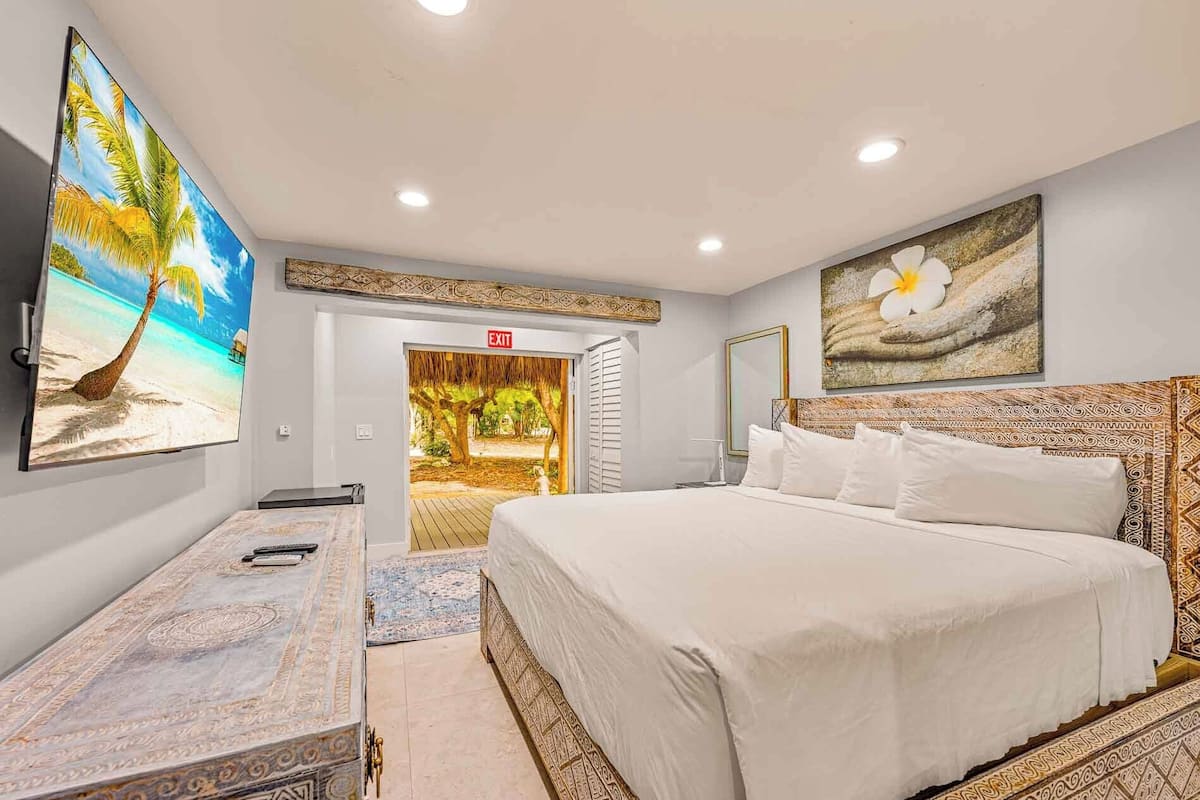 A hotel room with a bed, a desk, a TV, and a door leading to a balcony.