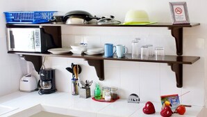 A kitchen with a microwave, toaster, coffee maker, and various kitchen utensils. There are red heart decorations on the wall and a plant on the counter. - Casa Frida Holbox (Isla Holbox)