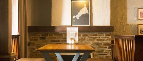 Una mesa de madera con estructura metálica, dos bancos acolchados, una pared de piedra y un mapa enmarcado en la pared.