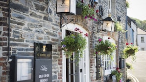 Un edificio de piedra con un cartel de St Austell Ale y un panel con la carta del Great Cornish Breakfast.