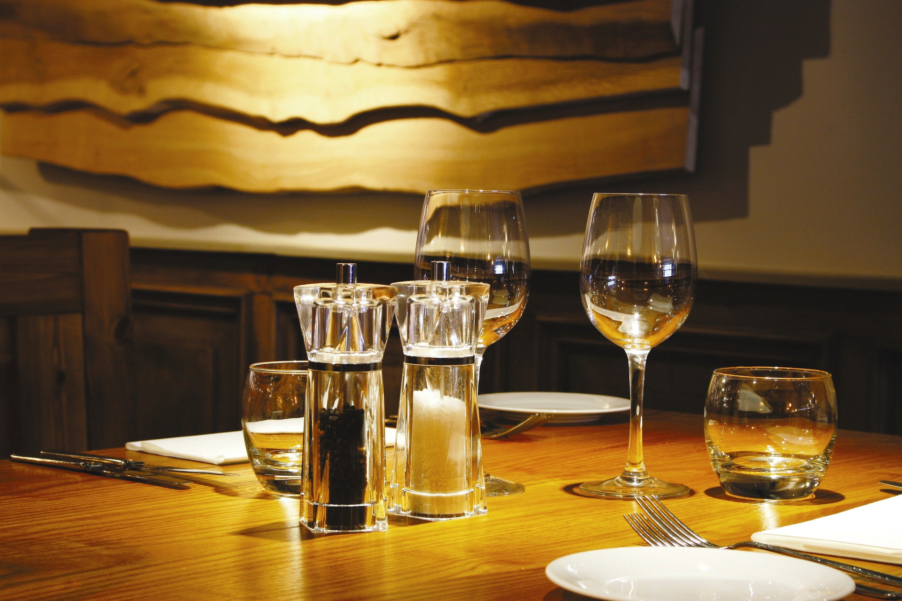 A dining table set with various glassware, including wine glasses and water glasses, and a salt and pepper shaker.