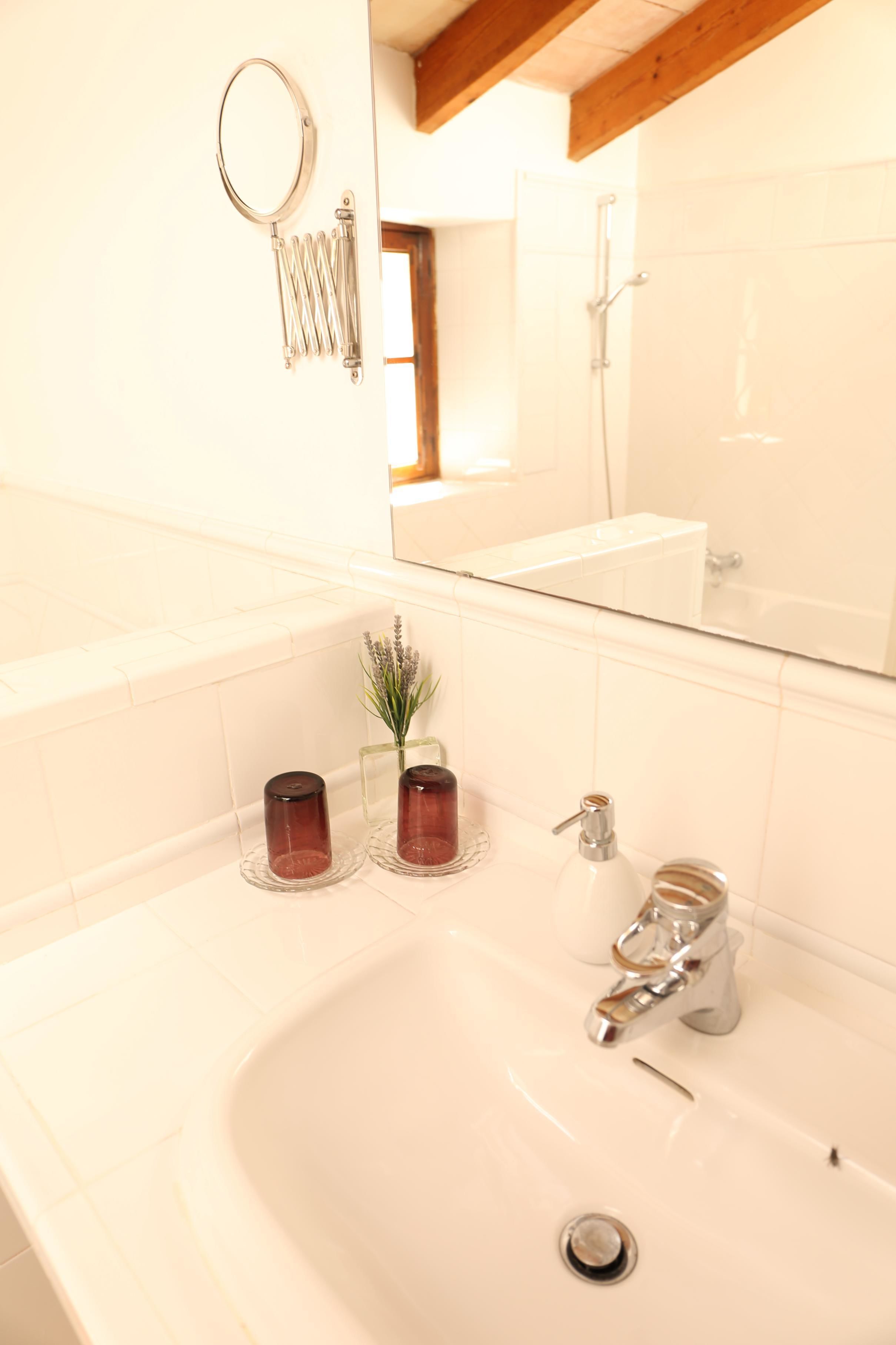 Ein Badezimmer mit einem weißen Waschbecken, einem Spiegel und einer Dusche.