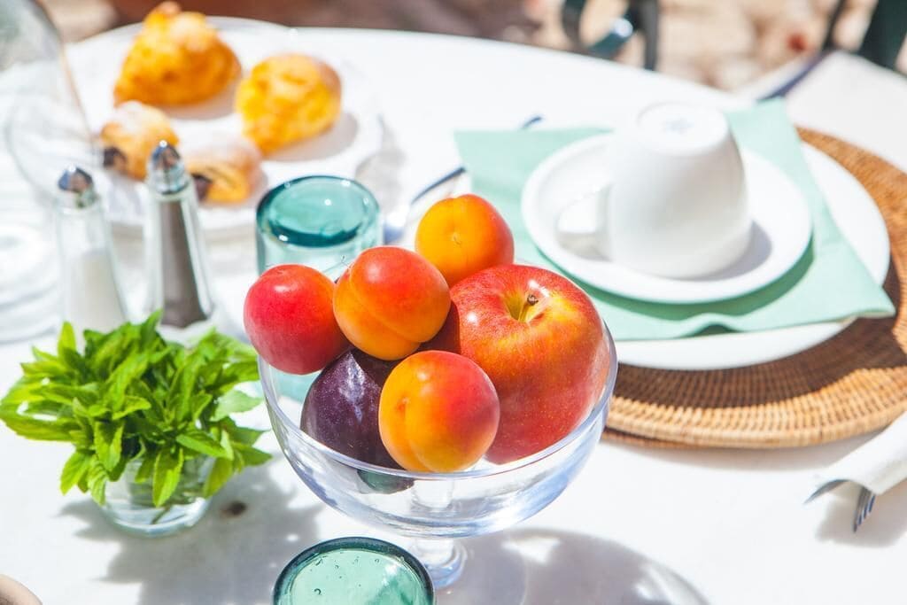A table with a bowl of fruit, a cup of coffee, and pastries.