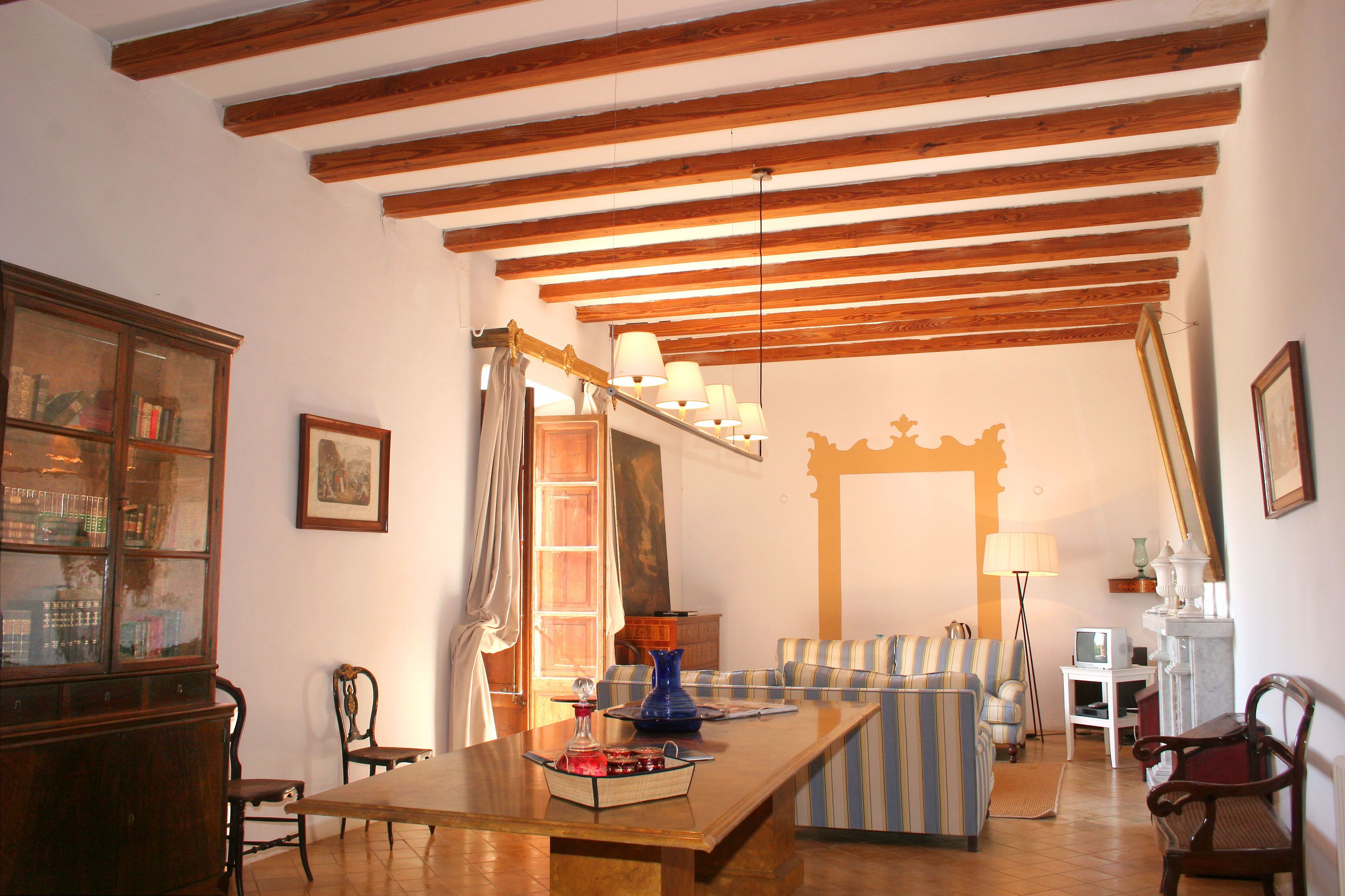 A living room with a wooden ceiling, a sofa, a dining table, and a cabinet.