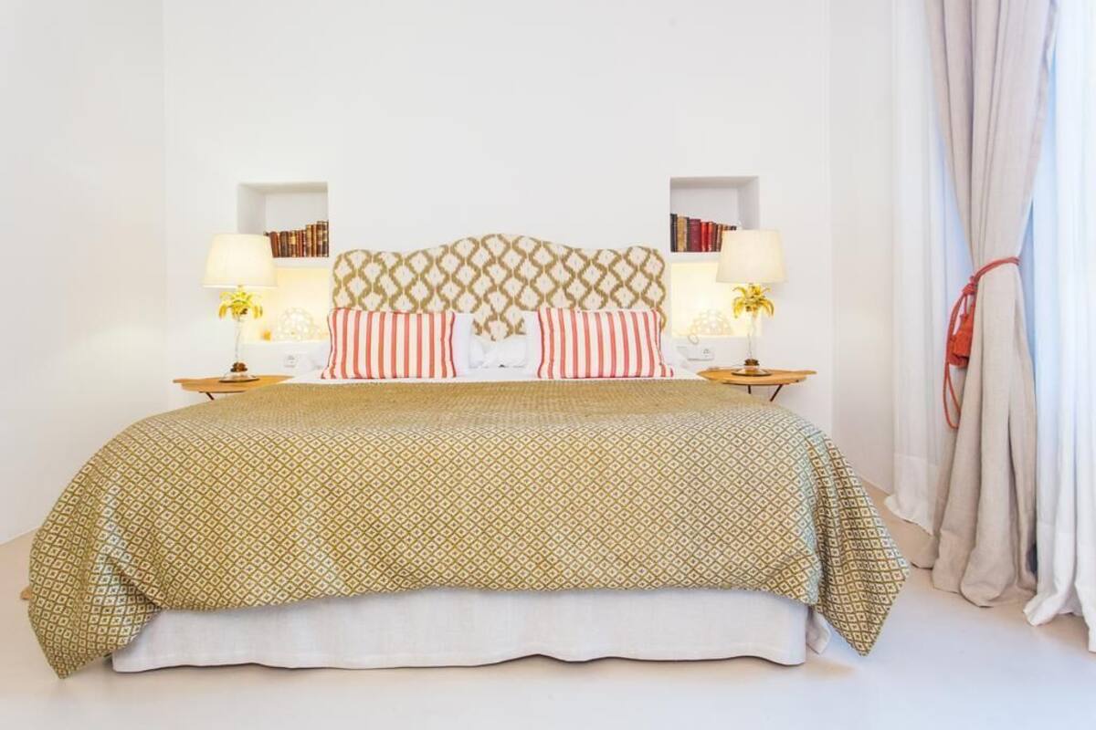 A neatly arranged bedroom with a patterned bedspread, striped pillows, and bedside lamps.