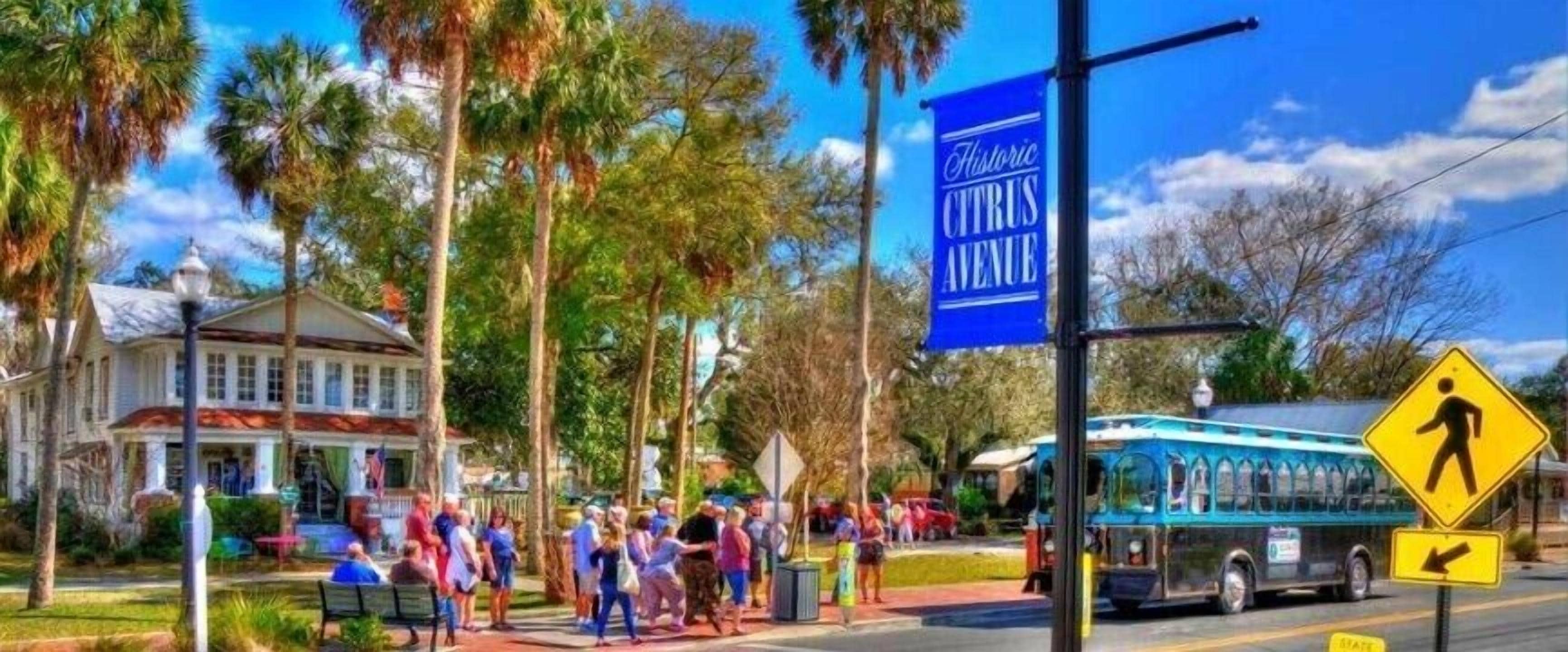 Zona histórica del centro con un letrero de Paisaje Histórico azul, una calle con peatones y un autobús.