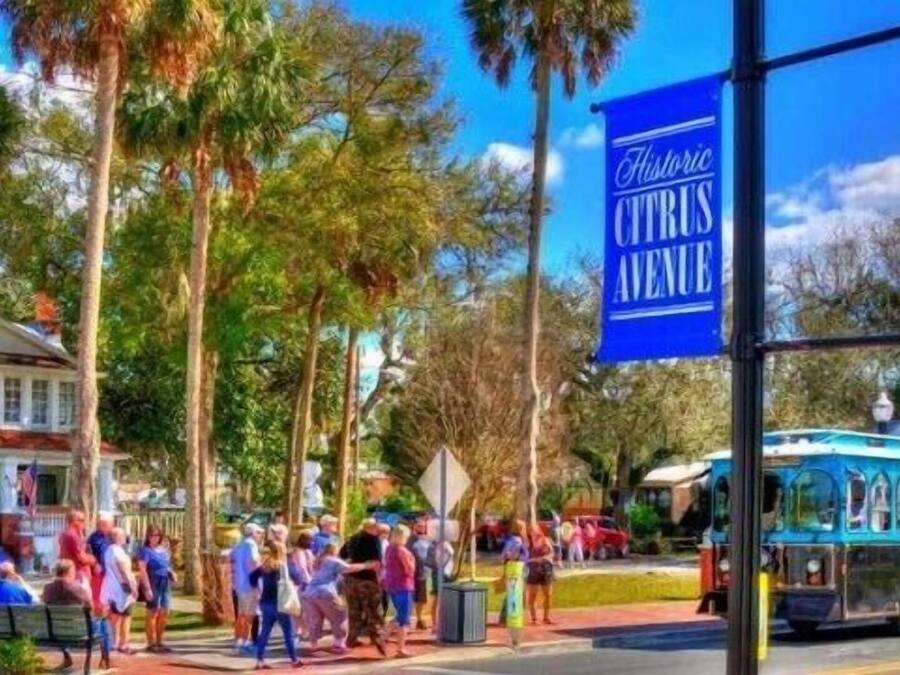 Zona histórica del centro con un letrero de Paisaje Histórico azul, una calle con peatones y un autobús.