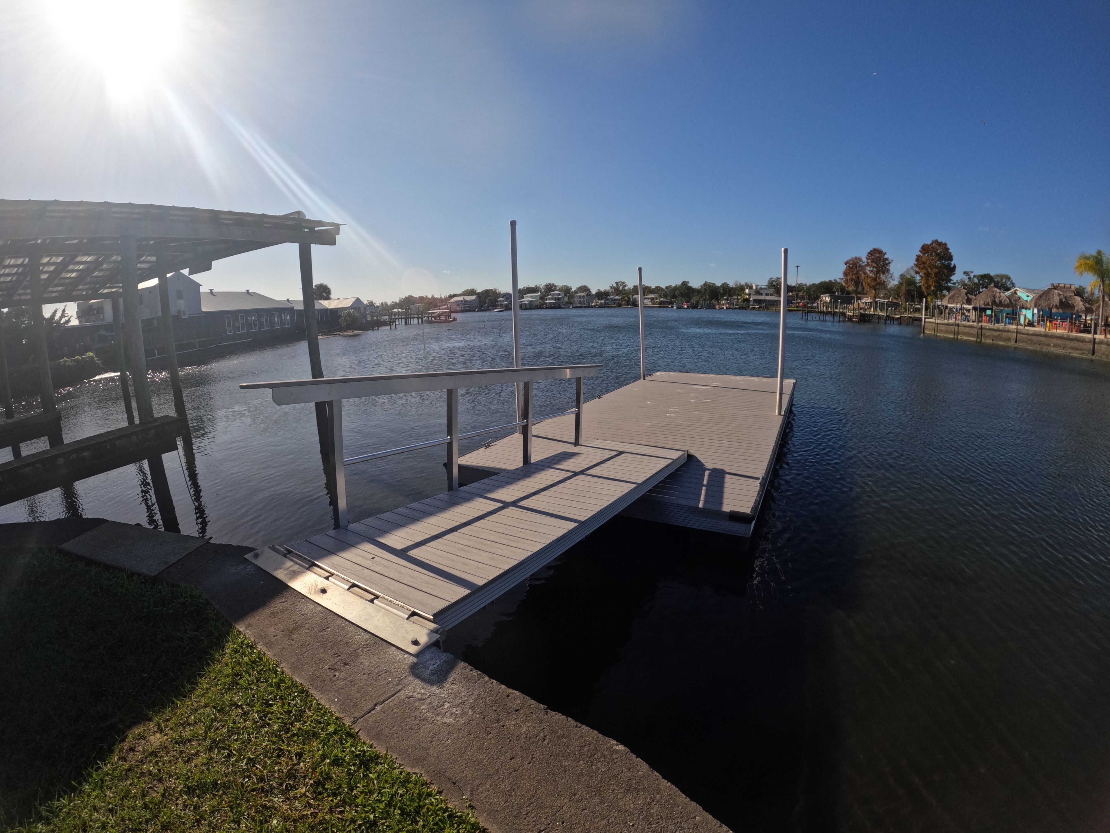 A wooden dock extending into a calm body of water, with a clear sky above.