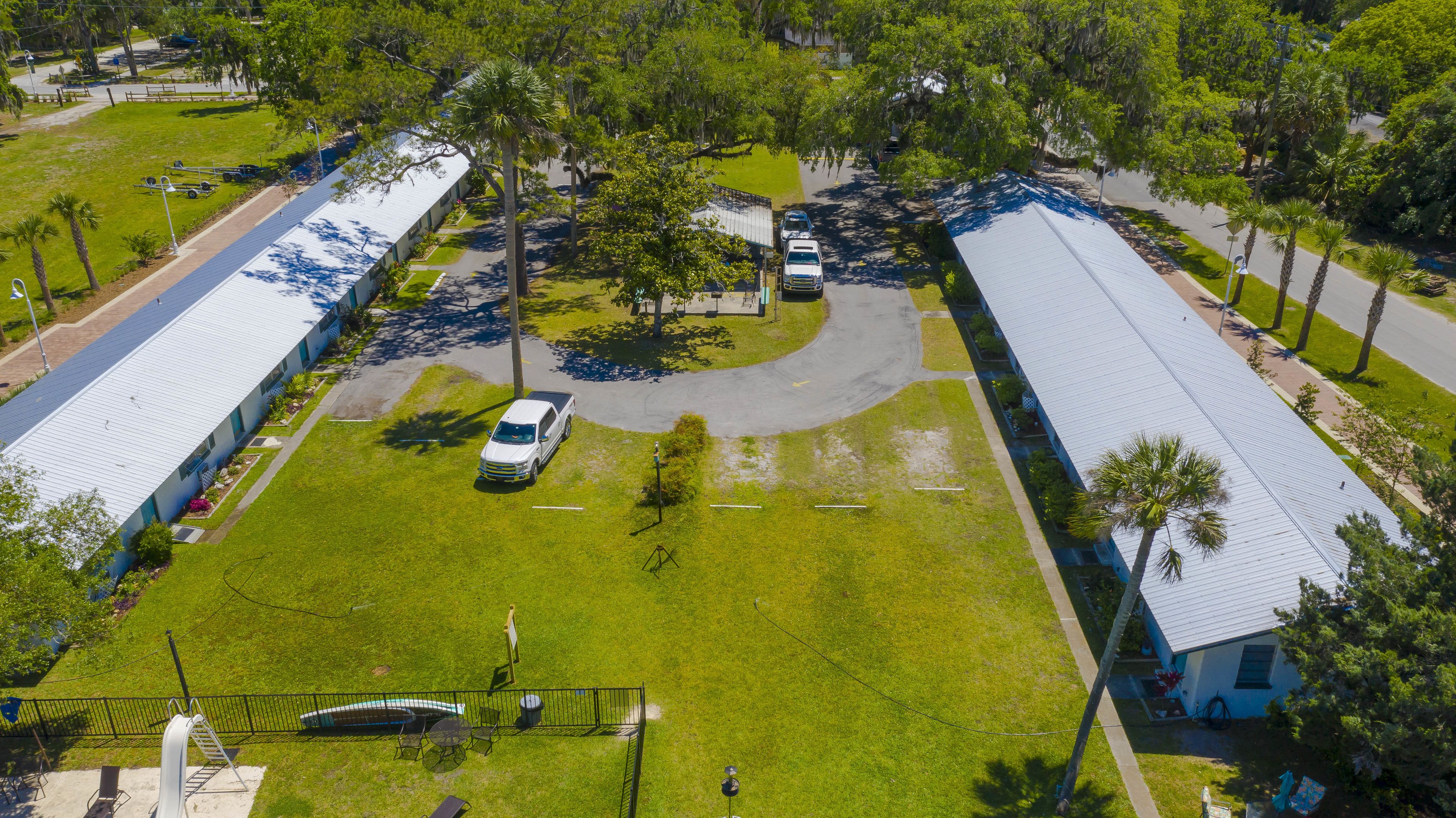 A large building with a flat roof, surrounded by a well-maintained lawn and palm trees.