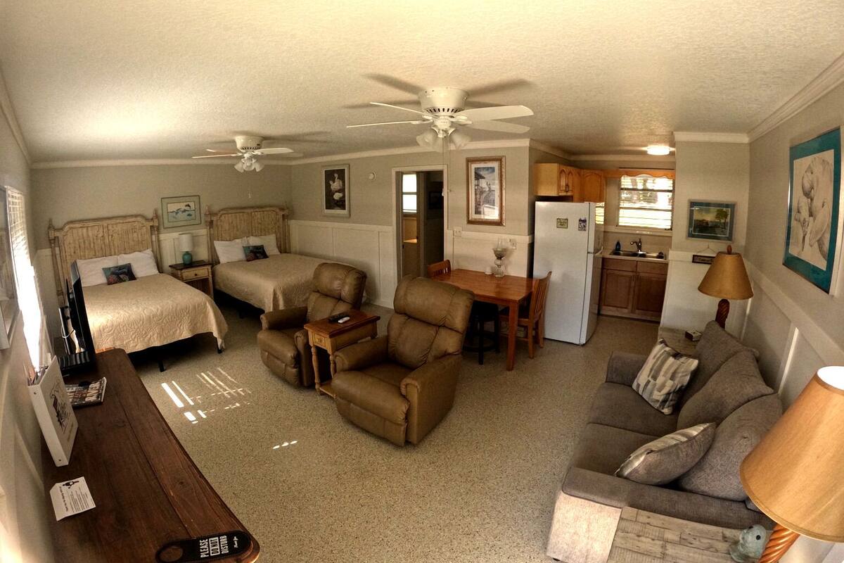 A compact living space with two bedrooms, a dining area, and a kitchenette.