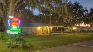 A motel named 'King's Bay' with a neon sign indicating vacancy and a 'Do Not Enter' sign.