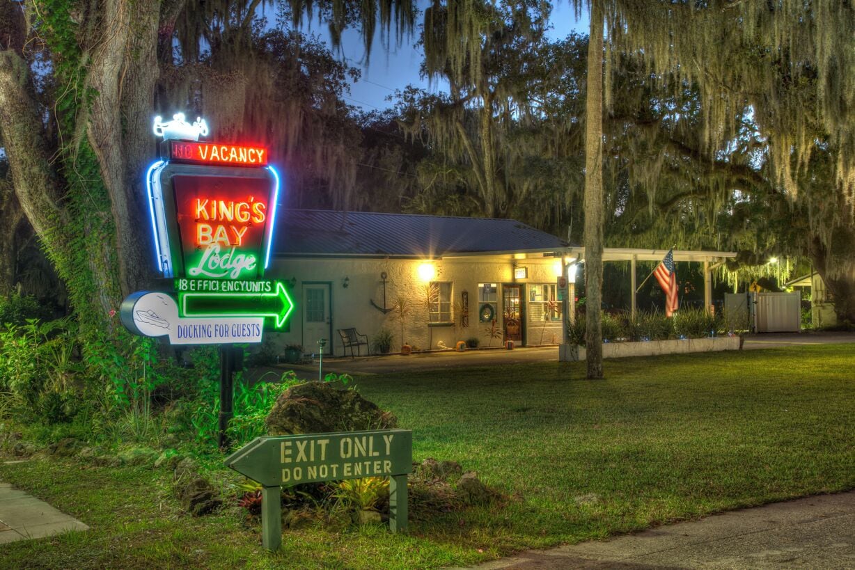 Un motel llamado King's Bay Lodge con un letrero de neón que indica 'no hay habitaciones disponibles' y amarre para embarcaciones de los huéspedes.