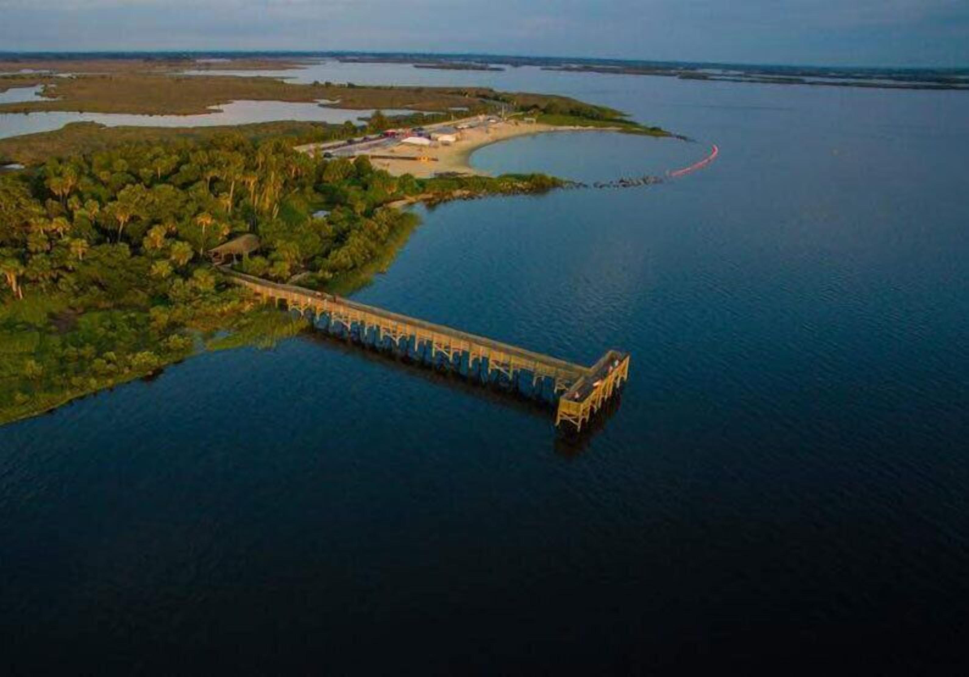 An aerial view of a bridge connecting two land masses over a large body of water.