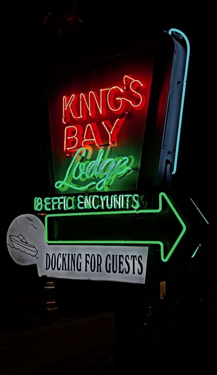 A neon sign for 'King's Bay Lodge' with a green arrow pointing to 'Docking for Guests'.