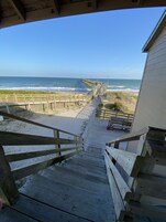 A wooden staircase leading to a beach with a wooden boardwalk and a view of the ocean.