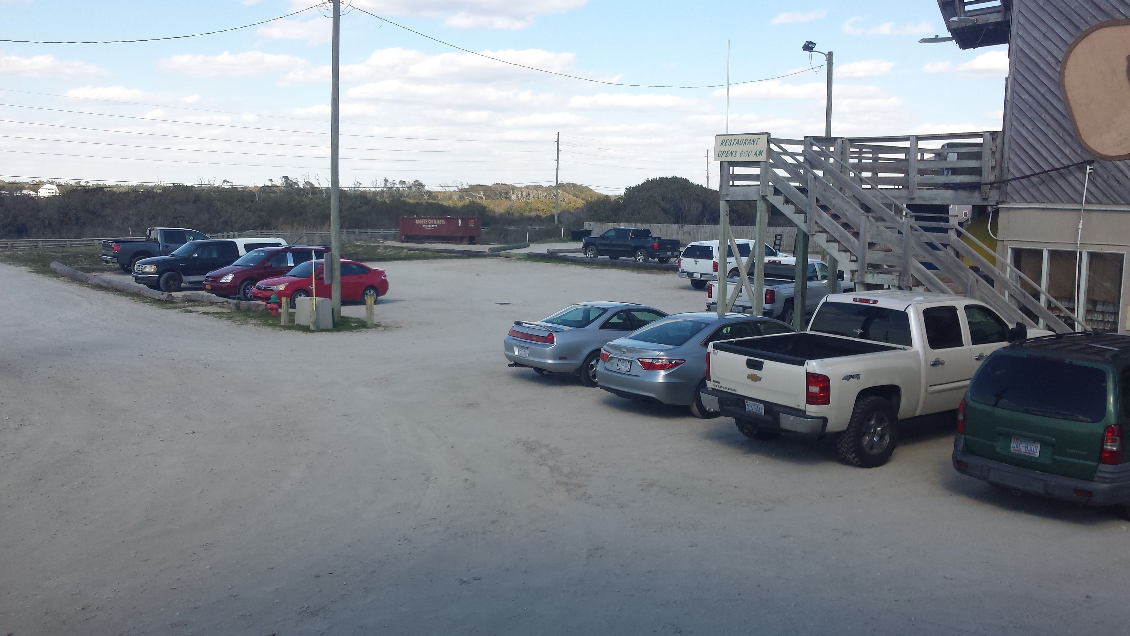 A parking lot with several cars, including a white pickup truck and a red sedan.