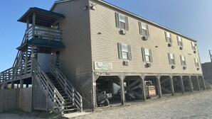 A two-story building with a balcony on the second floor, a staircase leading to the balcony, and a sign indicating a motel and office. - Seaview Pier and Motel (Sneads Ferry)