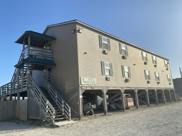 A two-story building with a balcony on the second floor, a staircase leading to the balcony, and a sign indicating a motel and office. - Seaview Pier and Motel (Sneads Ferry)