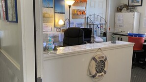 A reception desk with a life preserver hanging, a desk lamp, a chair, and a ceiling fan. - Seaview Pier and Motel (Sneads Ferry)