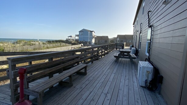 A wooden deck with benches and a red fire hydrant, overlooking a beach and buildings. - Seaview Pier and Motel (Sneads Ferry)