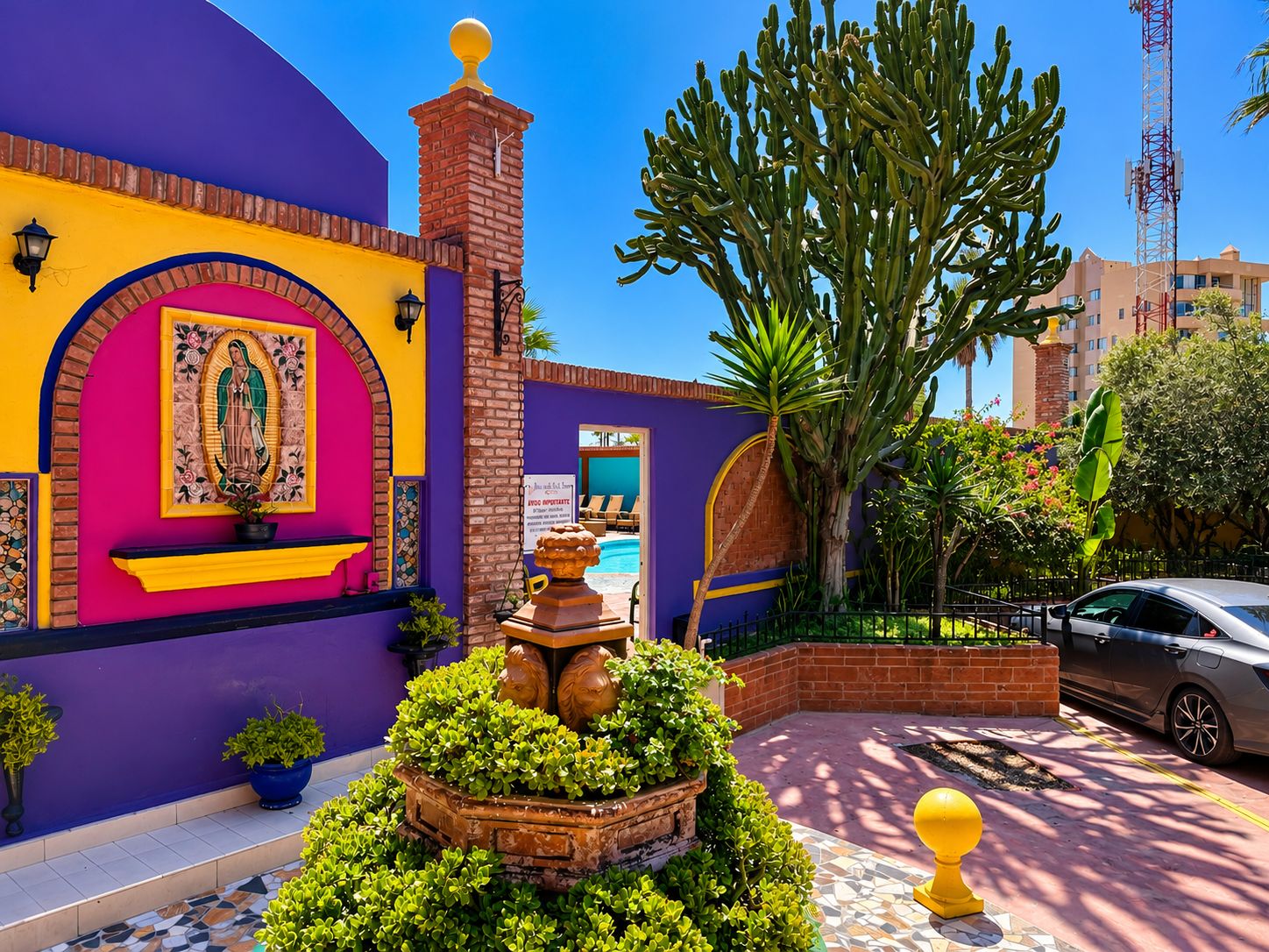 Un patio vibrante con piscina, una estatua y una gran planta de cactus.