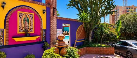 A vibrant courtyard with a pool, a statue, and a large cactus plant.