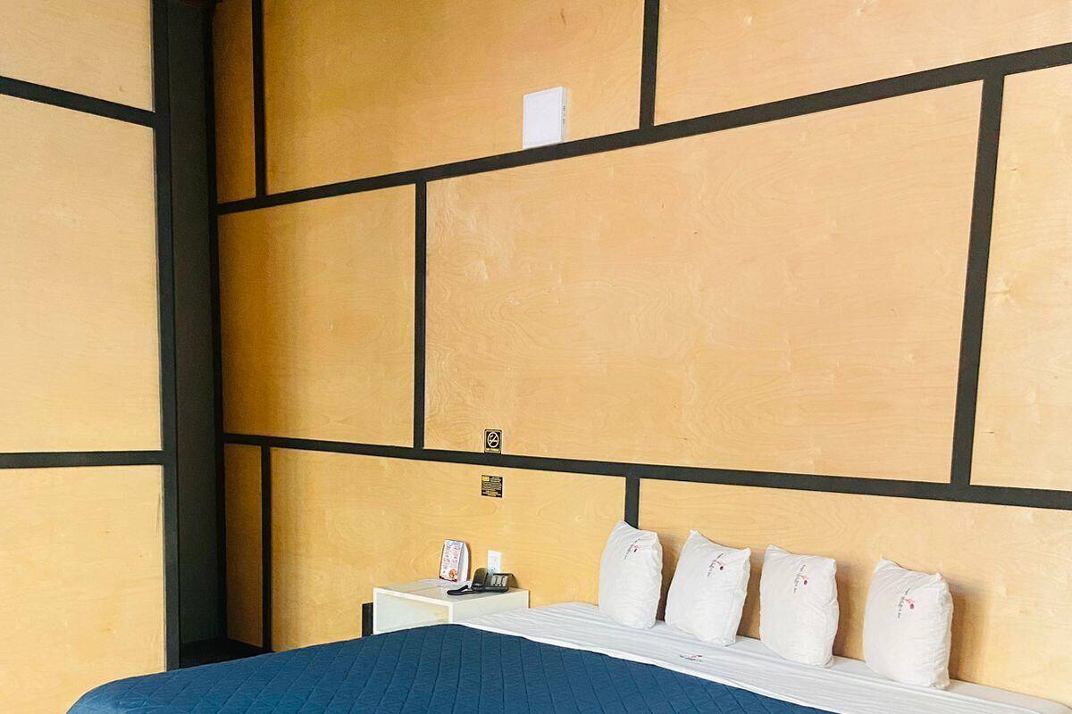 A hotel room with a large bed, a nightstand, and a wall with a geometric pattern.