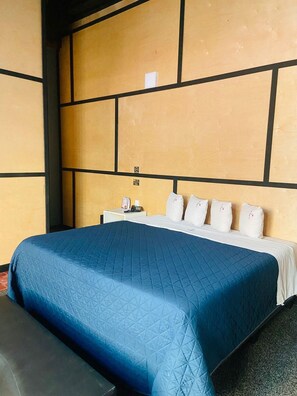 A hotel room with a large bed, a nightstand, and a wall with a geometric pattern. - Hotel Baja del Sol Inn (Playas de Rosarito)