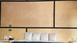 A hotel room with a large bed, a wooden headboard, and a nightstand with a phone and a menu. - Hotel Baja del Sol Inn (Playas de Rosarito)
