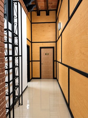 Un couloir avec une porte en bois portant l’inscription « 120 » et une grille métallique sur le côté gauche.